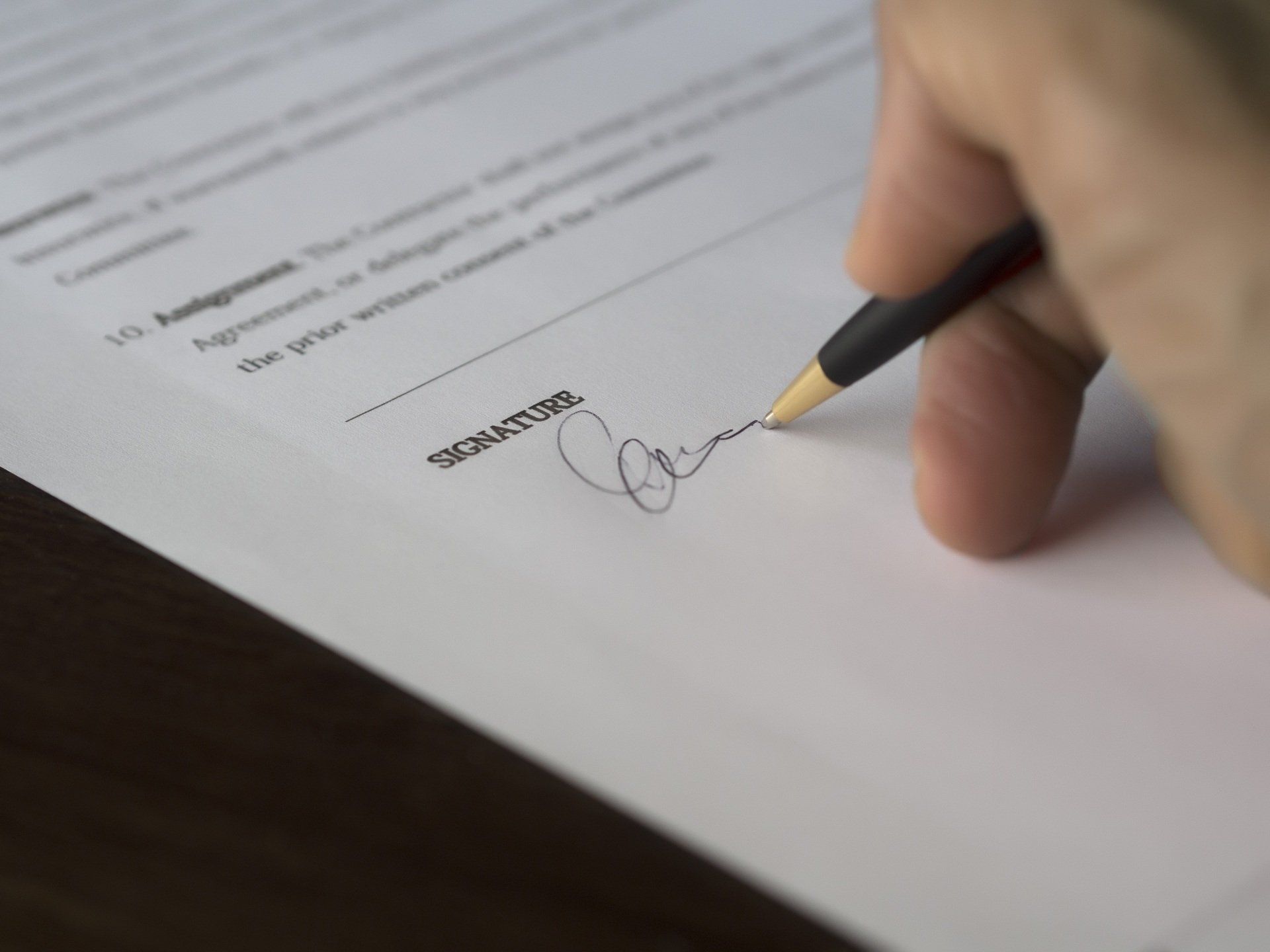 Hand signing a document with a pen on a white page