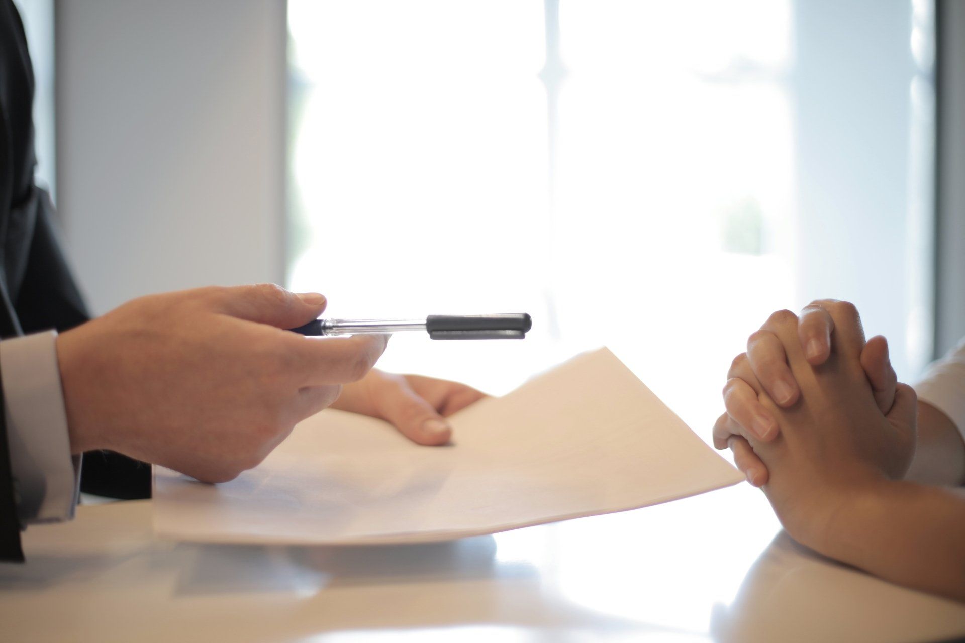 Hands at a desk with a pen and paperwork during a business meeting