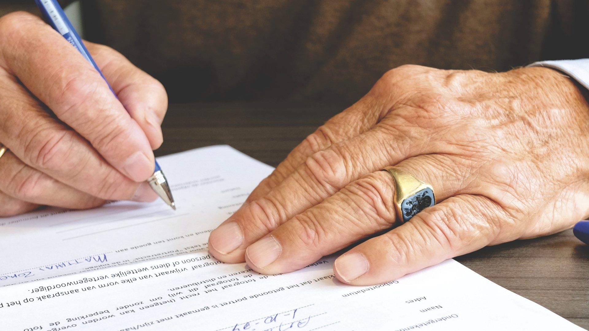 Hands signing a document with a pen on a desk